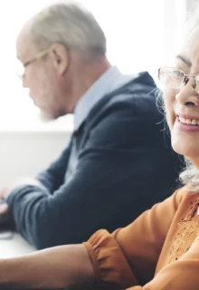 older woman smiles while a young woman and an older man talk in the background