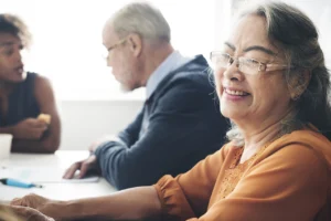 older woman smiles while a young woman and an older man talk in the background