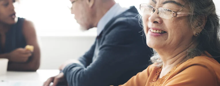 older woman smiles while a young woman and an older man talk in the background