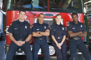 Firefighters leaning against a red fire truck