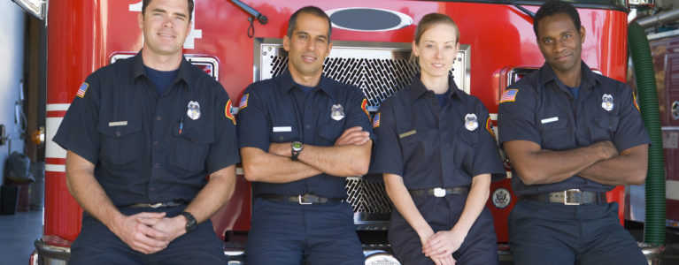 Firefighters leaning against a red fire truck