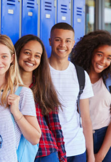 smiling teens lined up in front of a wall of blue lockers