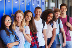 smiling teens lined up in front of a wall of blue lockers