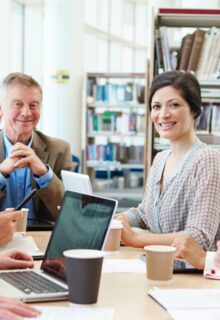 various smiling adults sit at a conference table