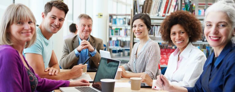 various smiling adults sit at a conference table