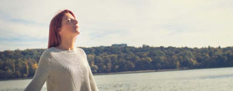 Woman breathing calmly in front of a lake