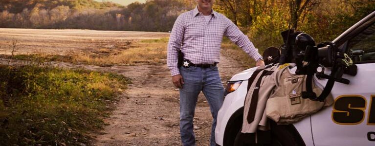 Derrick Sanders in front of a police vehicle