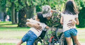 a veteran in a wheelchair hugging their children