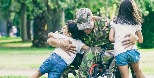 a veteran in a wheelchair hugging their children