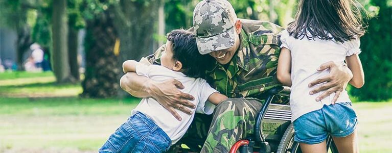 a veteran in a wheelchair hugging their children