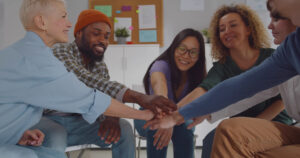 people smiling putting their hands in a circle