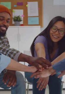 people smiling putting their hands in a circle