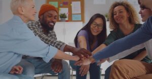 people smiling putting their hands in a circle