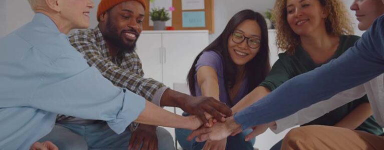 people smiling putting their hands in a circle