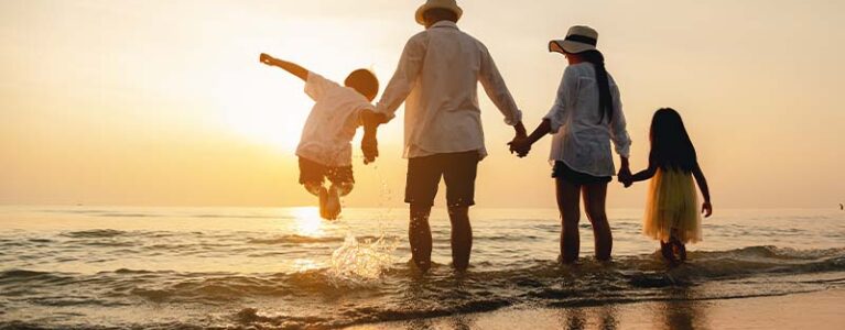 a family playing on the beach at sunset