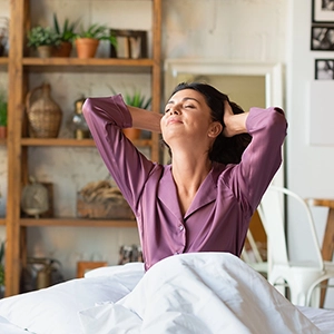 woman sitting in bed and stretching luxuriously