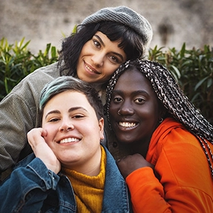 three smiling diverse young people snuggle up together