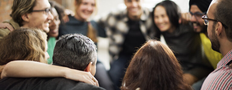 group of smiling people huddling in a circle