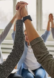 circle of people holding hands raised in the air