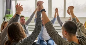 circle of people holding hands raised in the air