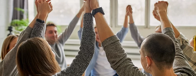 circle of people holding hands raised in the air