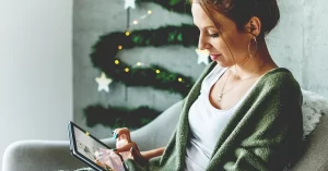 woman using an ipad in a room decorated for winter holidays