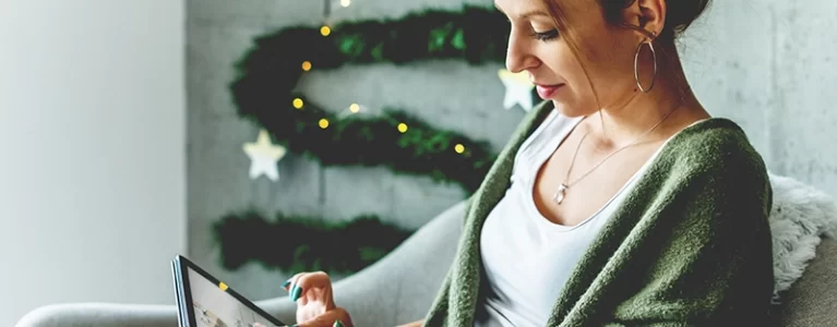 woman using an ipad in a room decorated for winter holidays