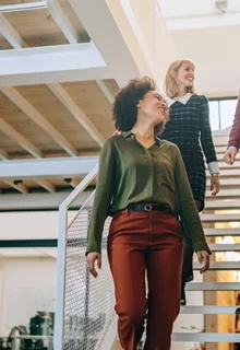 four smiling colleagues walk down a sunlit staircase together