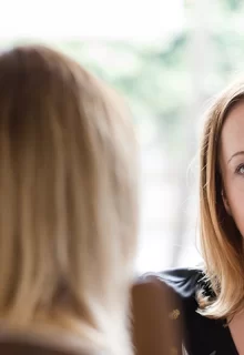 two women talk across a kitchen table