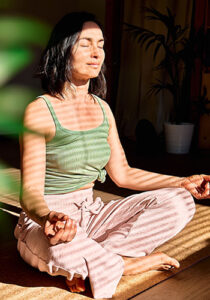 a woman sitting with legs crossed and eyes closed