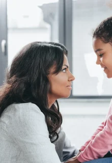 a mother and young daughter face each other