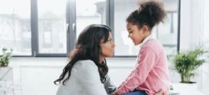 a mother and young daughter face each other