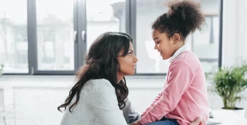a mother and young daughter face each other