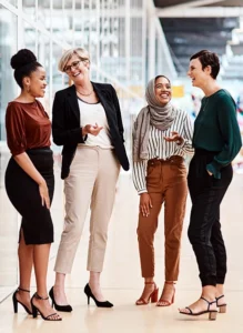 four women chat in an office setting