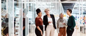 four women chat in an office setting