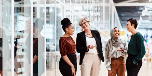 four women chat in an office setting