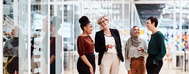 four women chat in an office setting