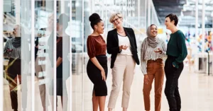 four women chat in an office setting