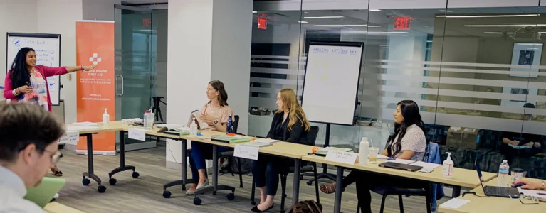 an instructor leads a mental health first aid course in a conference room