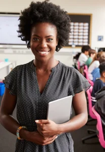 smiling teacher with students working at computers behind her