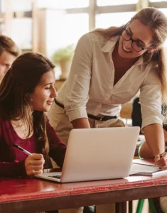 a smiling teacher helps students with their work