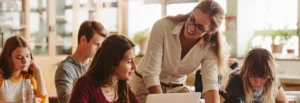 a smiling teacher helps students with their work