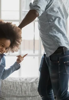 dad and two young kids dance around the living room