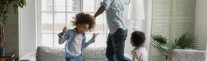 dad and two young kids dance around the living room