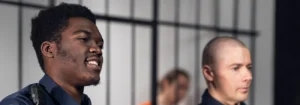 two corrections officers stand in front of a jail cell