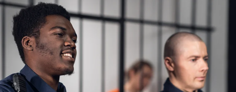 two corrections officers stand in front of a jail cell