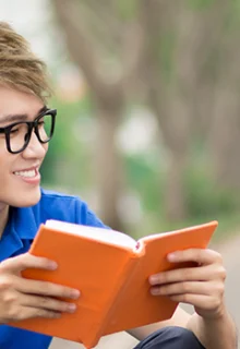 two teen boys reading books and talking on a sidewalk