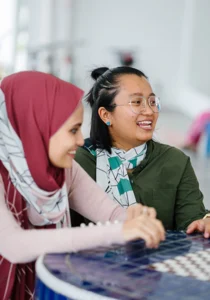 two smiling young women sit at a cafe table