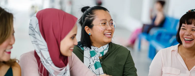 four smiling young women sit at a cafe table