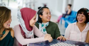 four smiling young women sit at a cafe table